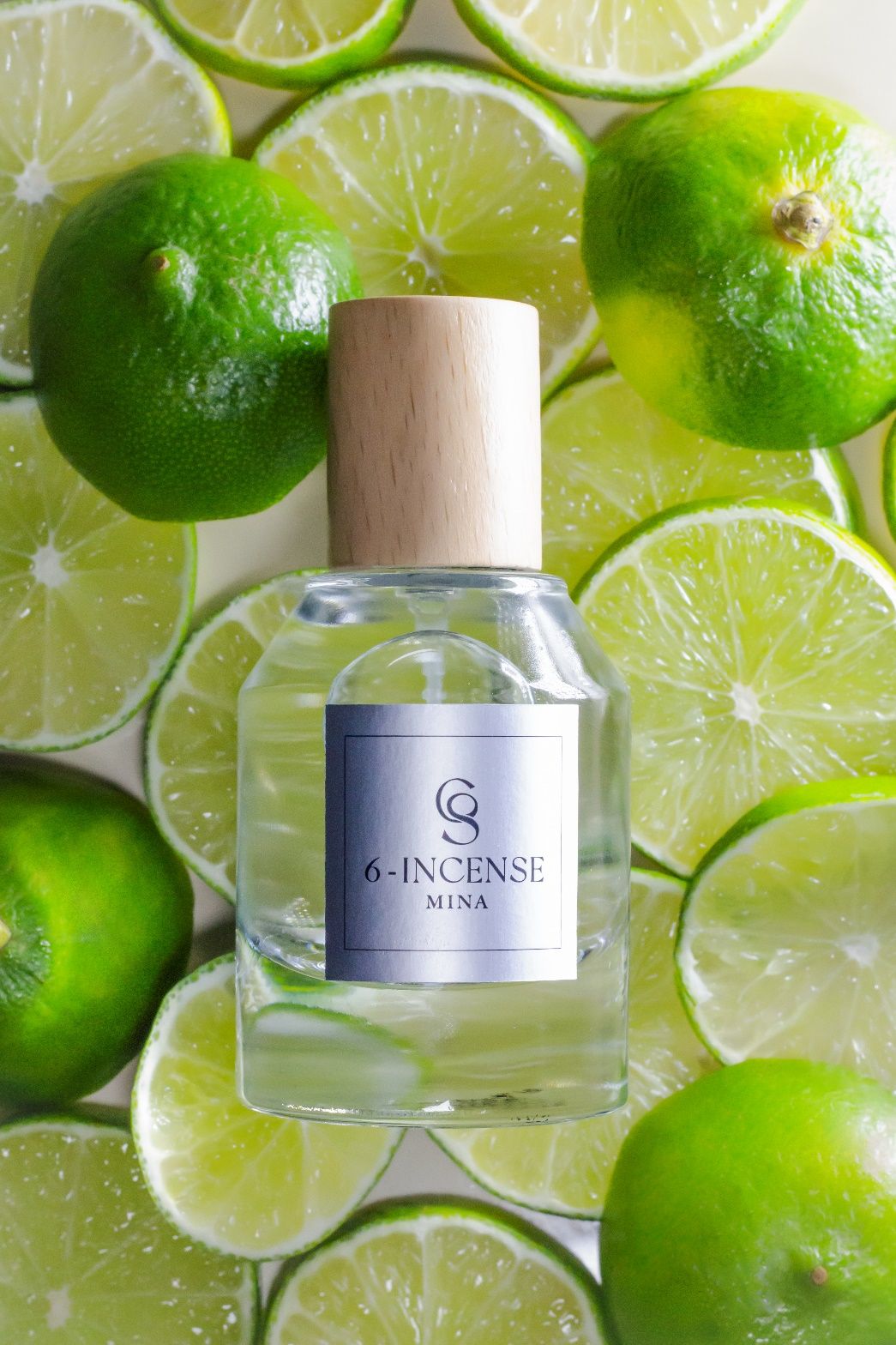A bottle of perfume on a pile of limes\n\nDescription automatically generated